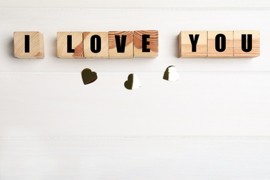 Photo of Phrase I Love You made of cubes on white wooden background, flat lay. Space for text