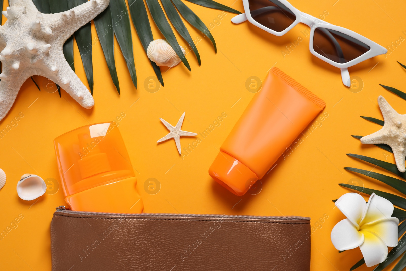 Photo of Flat lay composition with sun protection products and beach accessories on orange background