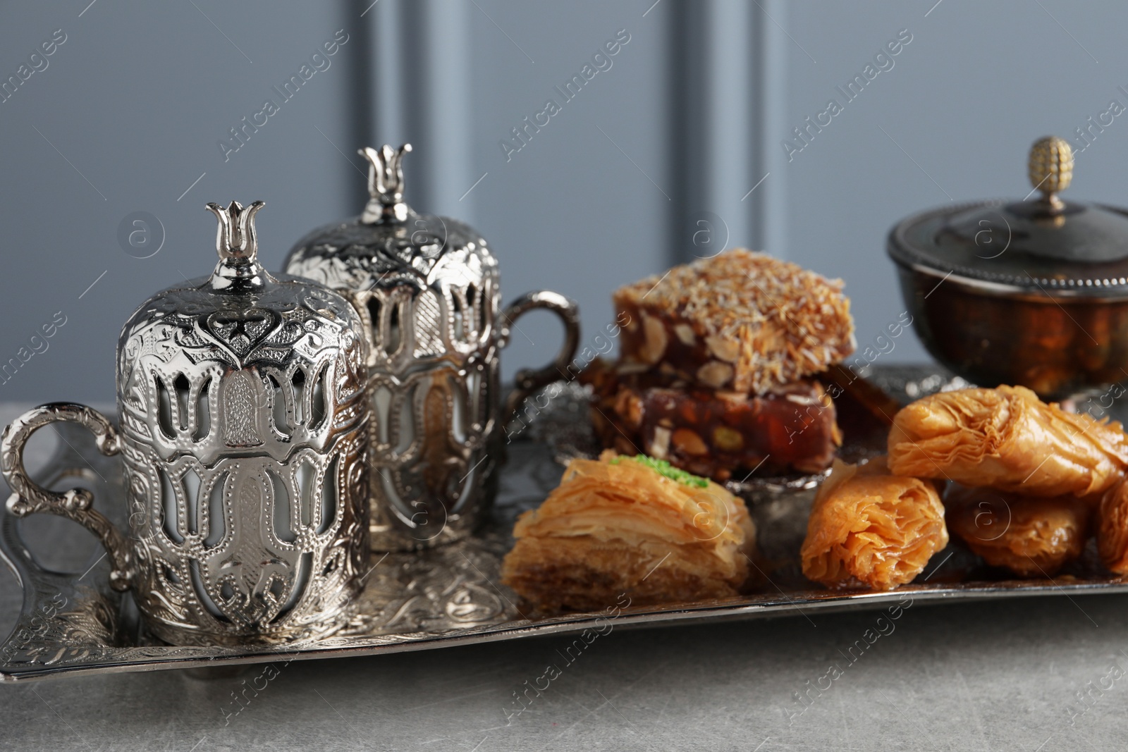 Photo of Tea, baklava dessert and Turkish delight served in vintage tea set on grey textured table, closeup