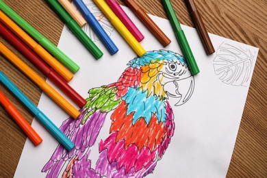 Photo of Child's colored drawing with felt tip pens on wooden table, flat lay