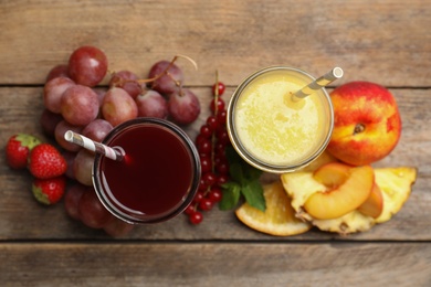 Photo of Delicious colorful juices in glasses and fresh ingredients on wooden table, flat lay