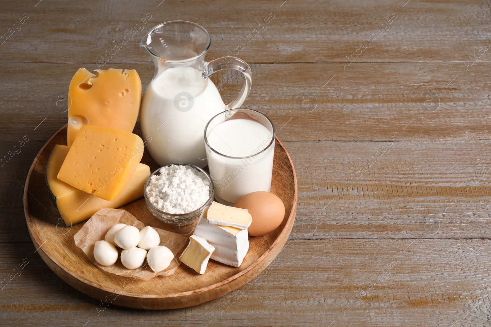 Photo of Different delicious dairy products on wooden table. Space for text