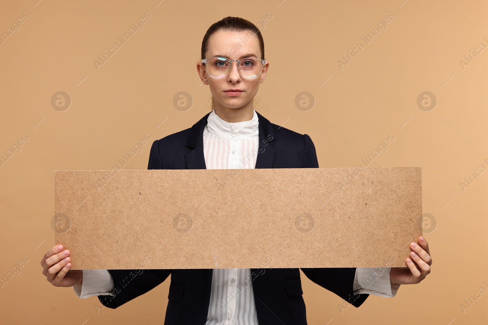 Photo of Beautiful woman holding blank cardboard banner on beige background, space for text