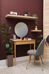 Wooden dressing table and chair near brown wall in room