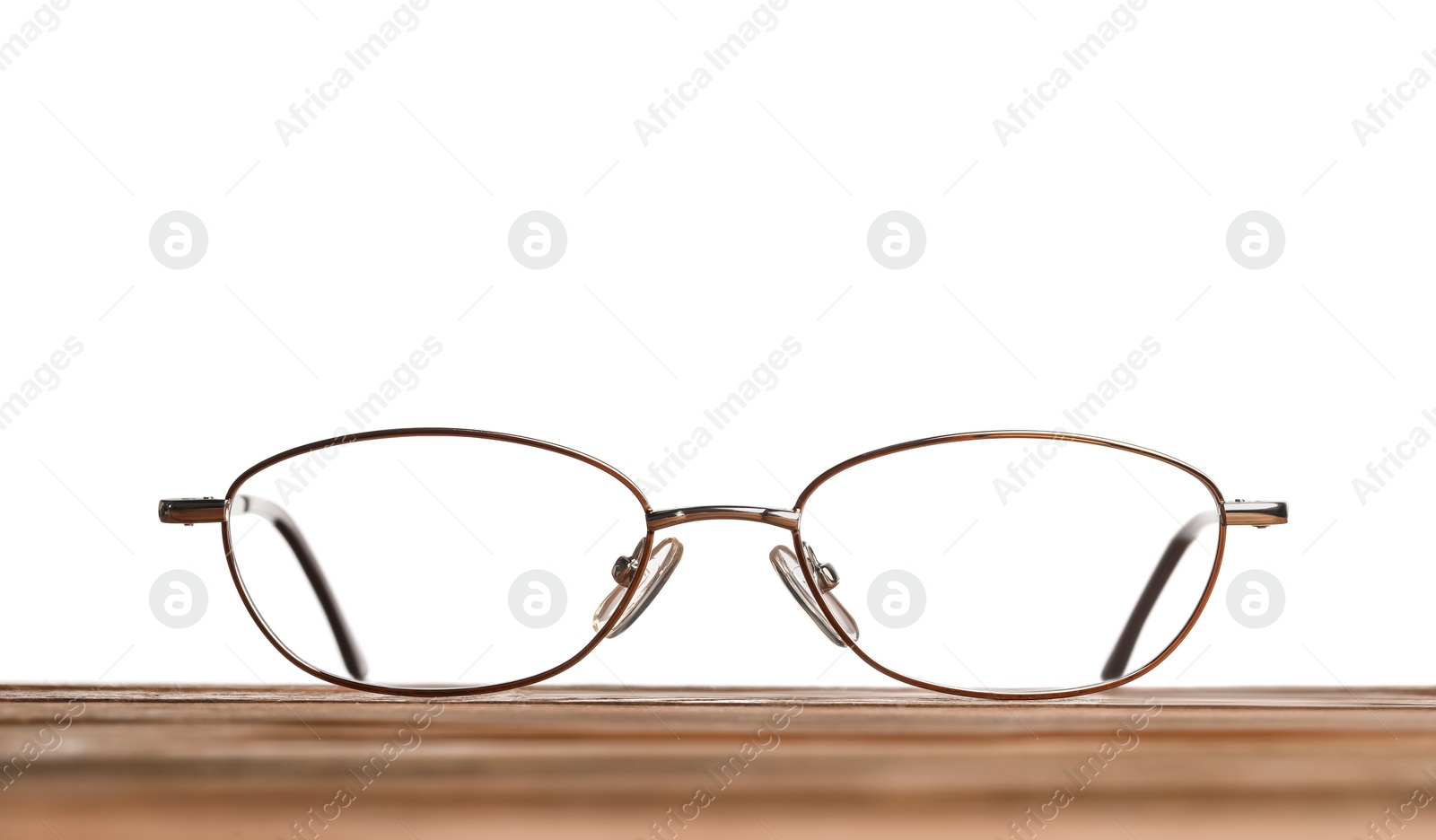 Photo of Stylish glasses with metal frame on wooden table against white background