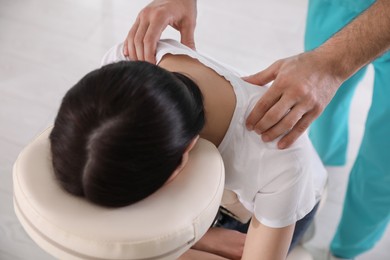 Photo of Woman receiving massage in modern chair indoors, above view