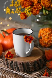 Photo of Beautiful autumn composition with cup of drink and flowers on wicker table