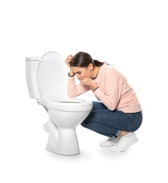 Young woman suffering from nausea near toilet bowl isolated on white