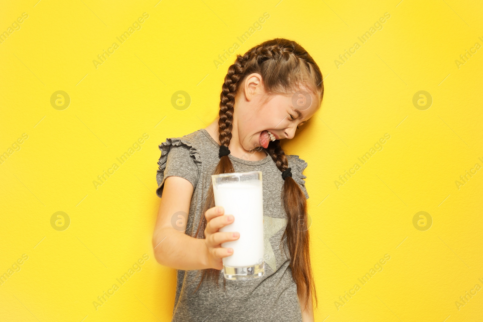 Photo of Little girl with dairy allergy holding glass of milk on color background