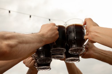 Photo of Friends clinking glasses with beer in outdoor cafe, closeup