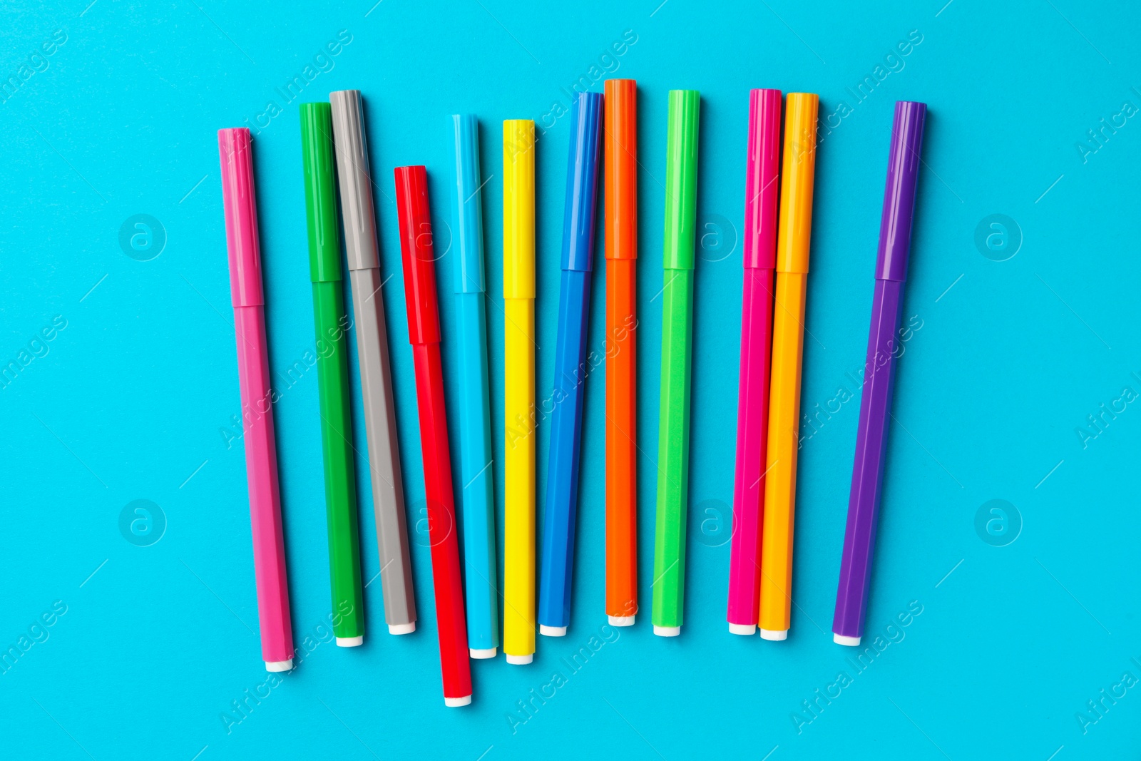 Photo of Many bright markers on light blue background, flat lay