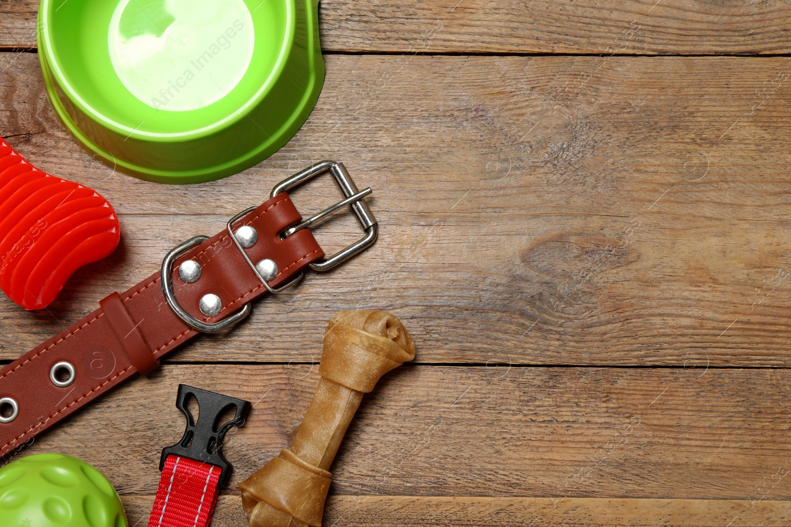 Photo of Flat lay composition with dog collar, toys and bowl on wooden table. Space for text