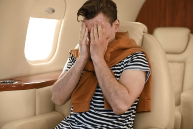 Young man feeling bad during flight in airplane