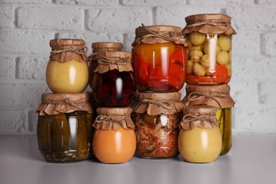 Many glass jars with different preserved products on light grey table