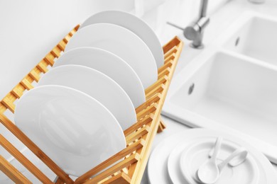 Photo of Drying rack with clean dishes on countertop near sink in kitchen, closeup