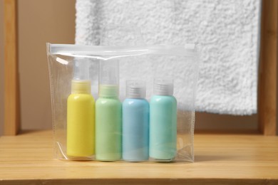Photo of Cosmetic travel kit in plastic bag on wooden table. Bath accessories
