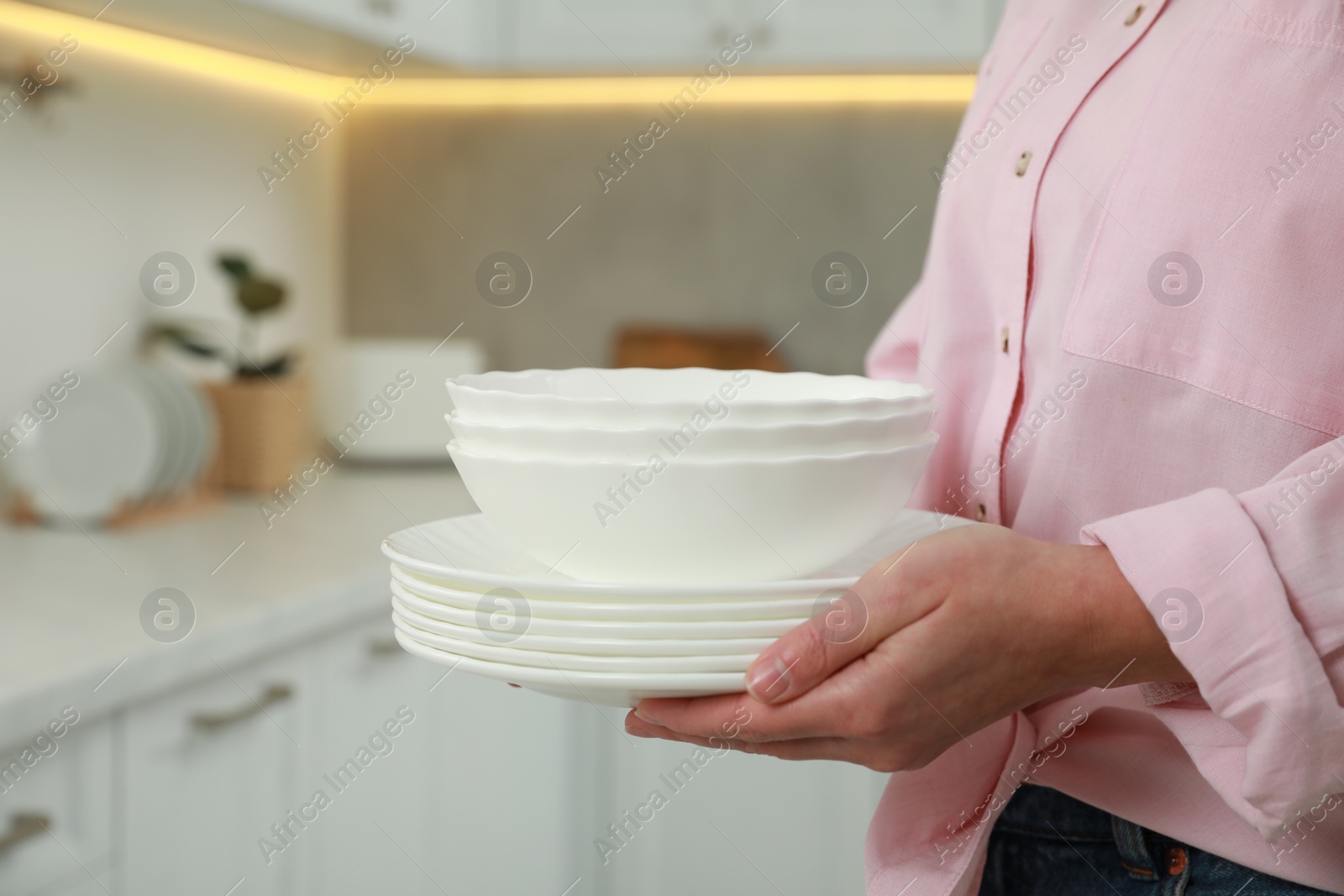 Photo of Woman holding plates in kitchen, closeup view