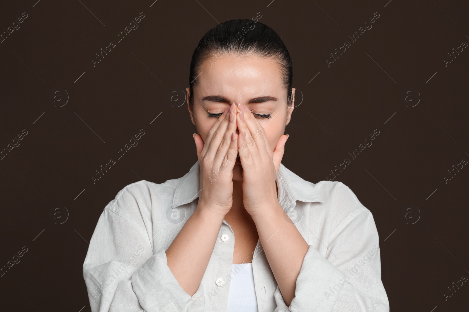 Photo of Young woman suffering from headache on dark brown background