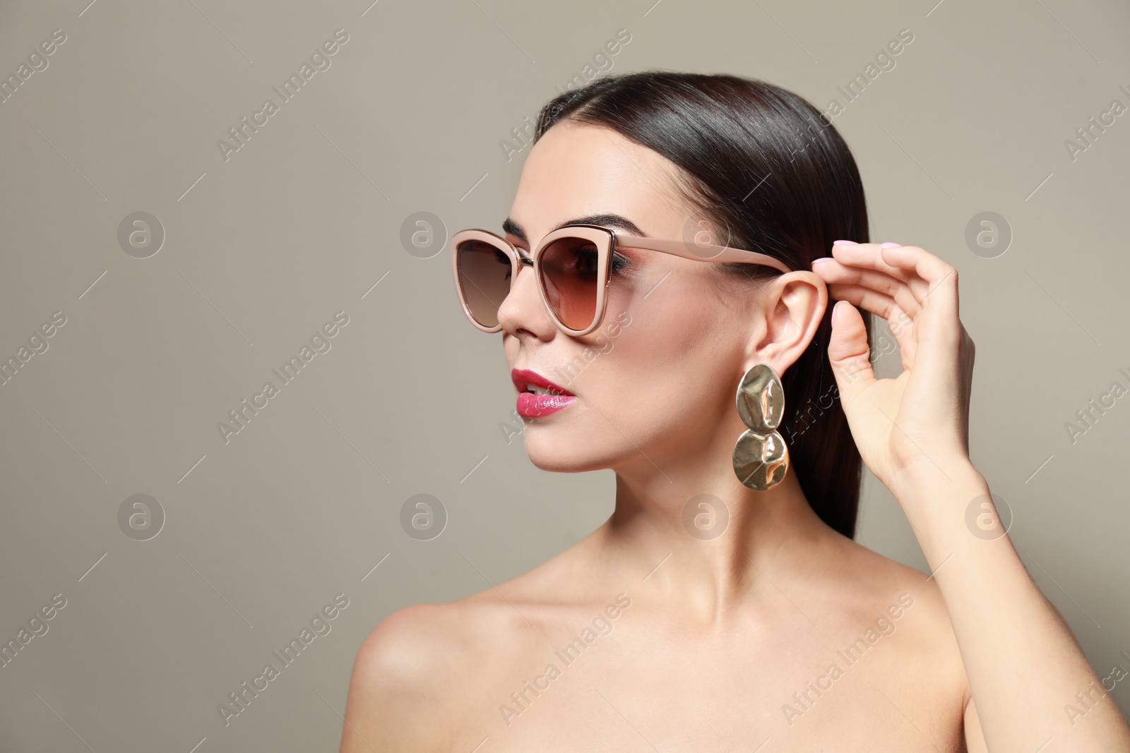 Photo of Beautiful woman in stylish sunglasses on beige background