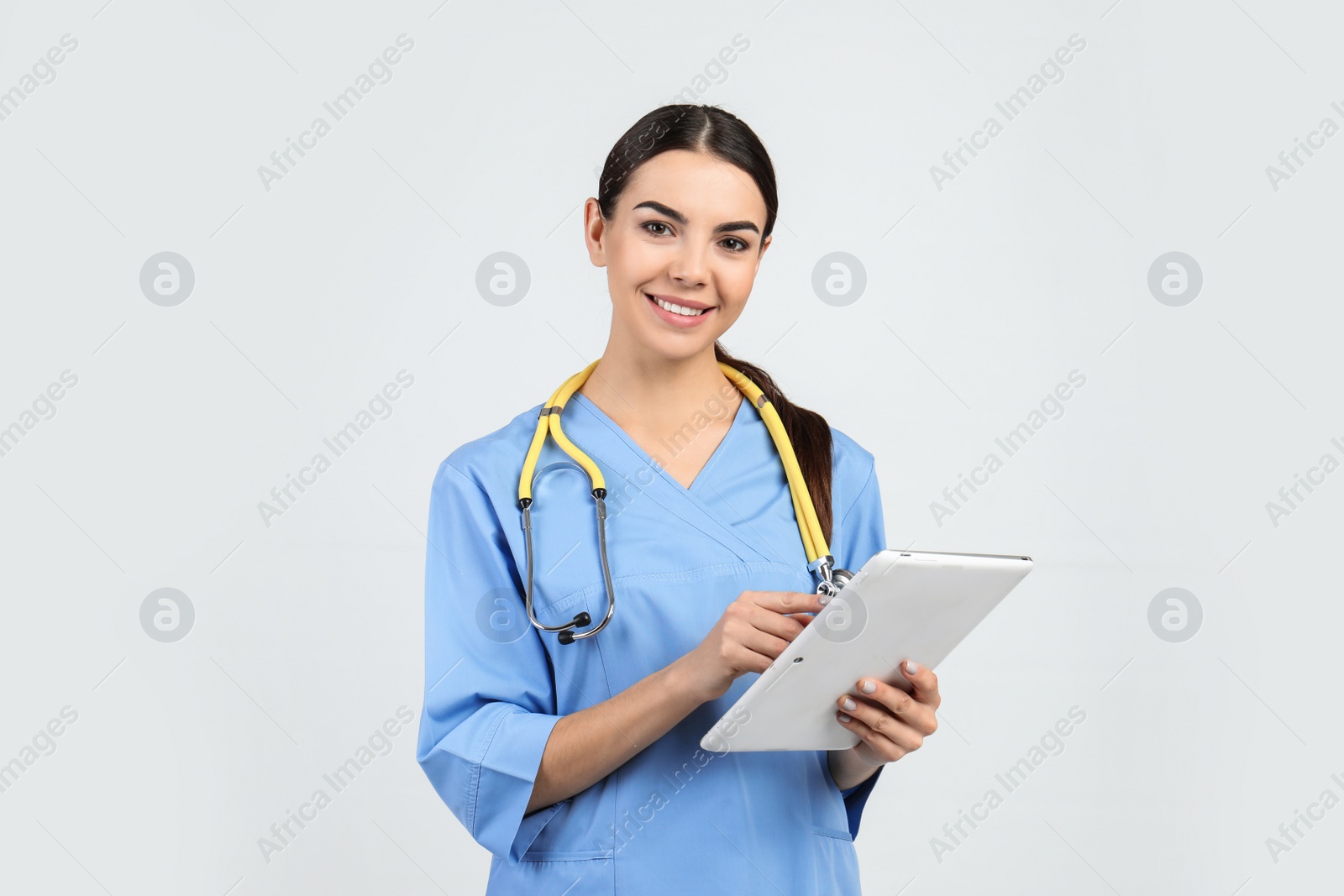 Photo of Portrait of medical assistant with stethoscope and tablet on light background