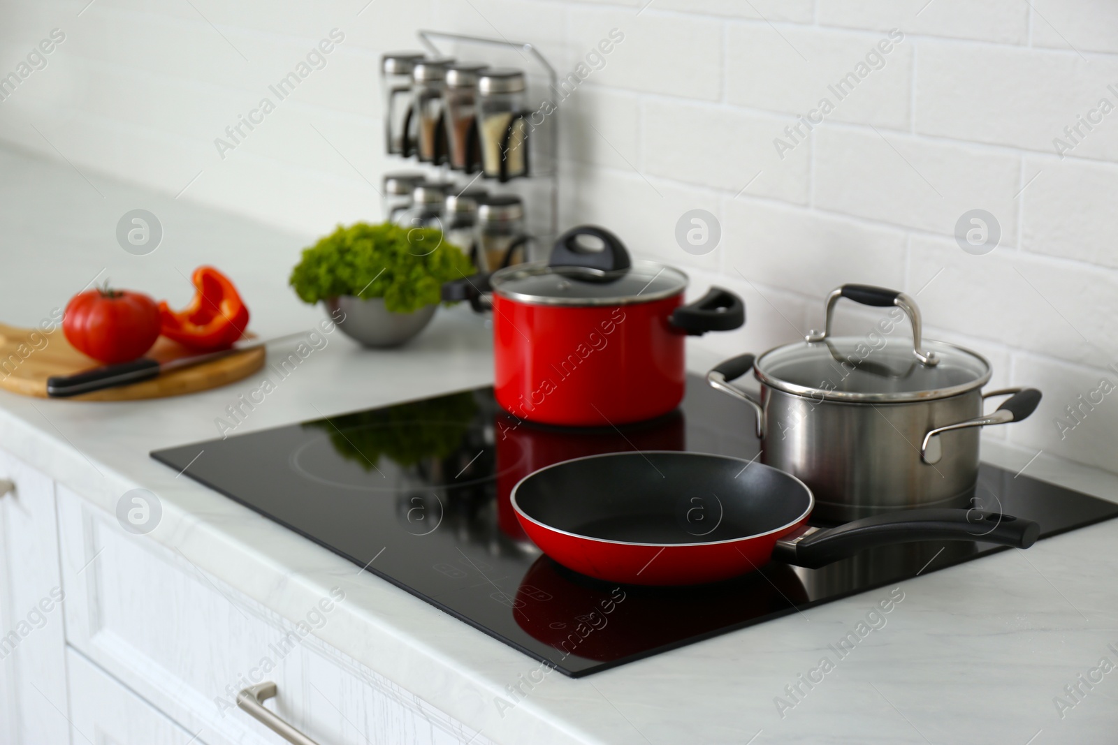 Photo of Saucepots and frying pan on induction stove in kitchen