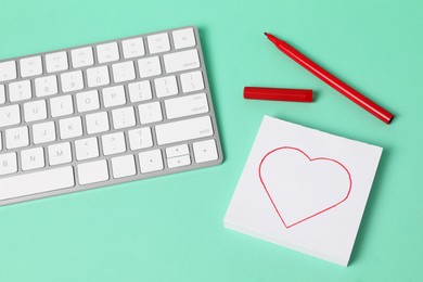 Photo of Long-distance relationship concept. Keyboard, love note and marker on turquoise background, above view