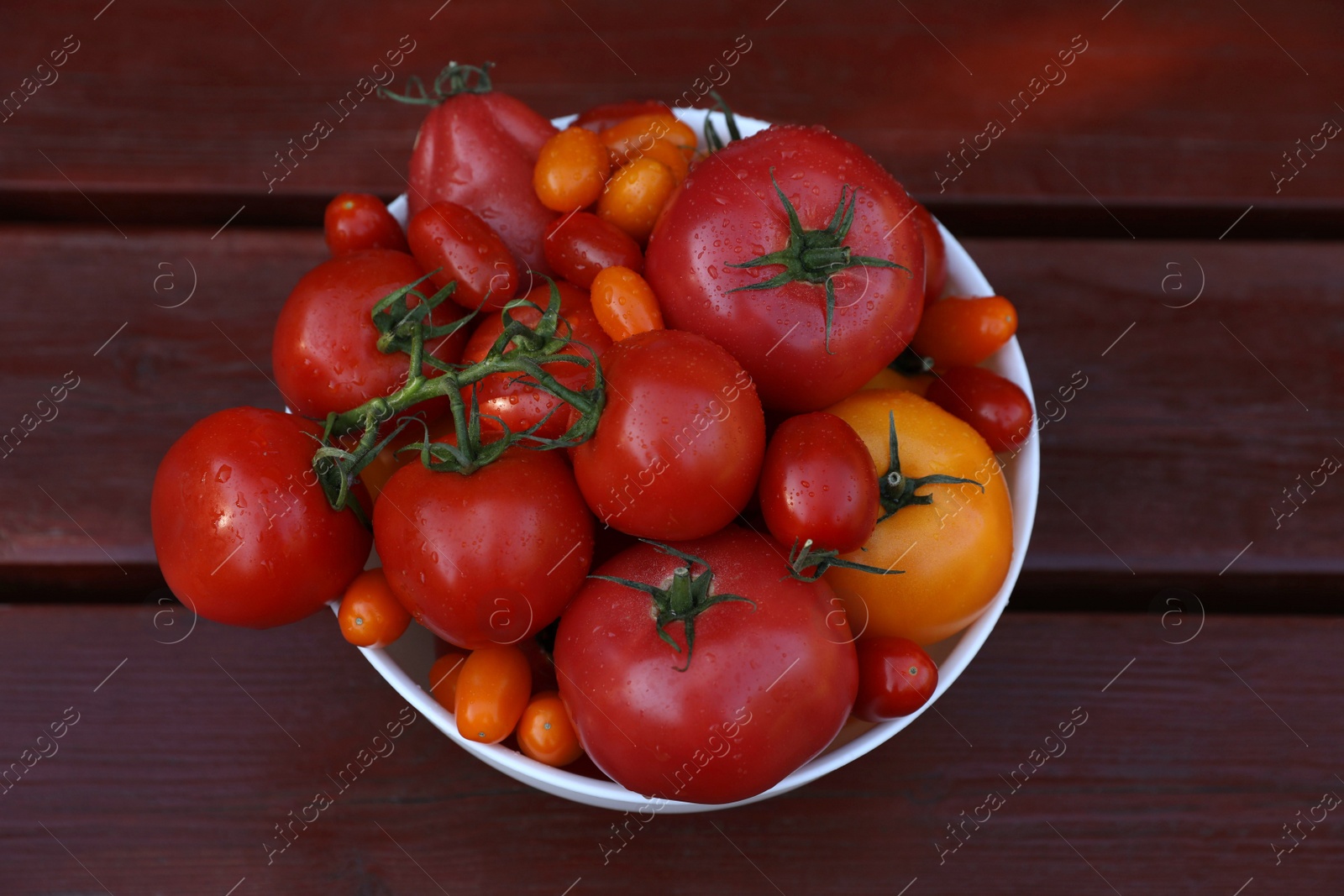 Photo of Bowl with fresh tomatoes on wooden table, top view