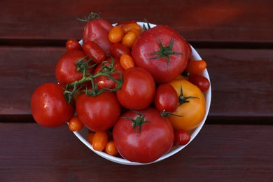Bowl with fresh tomatoes on wooden table, top view