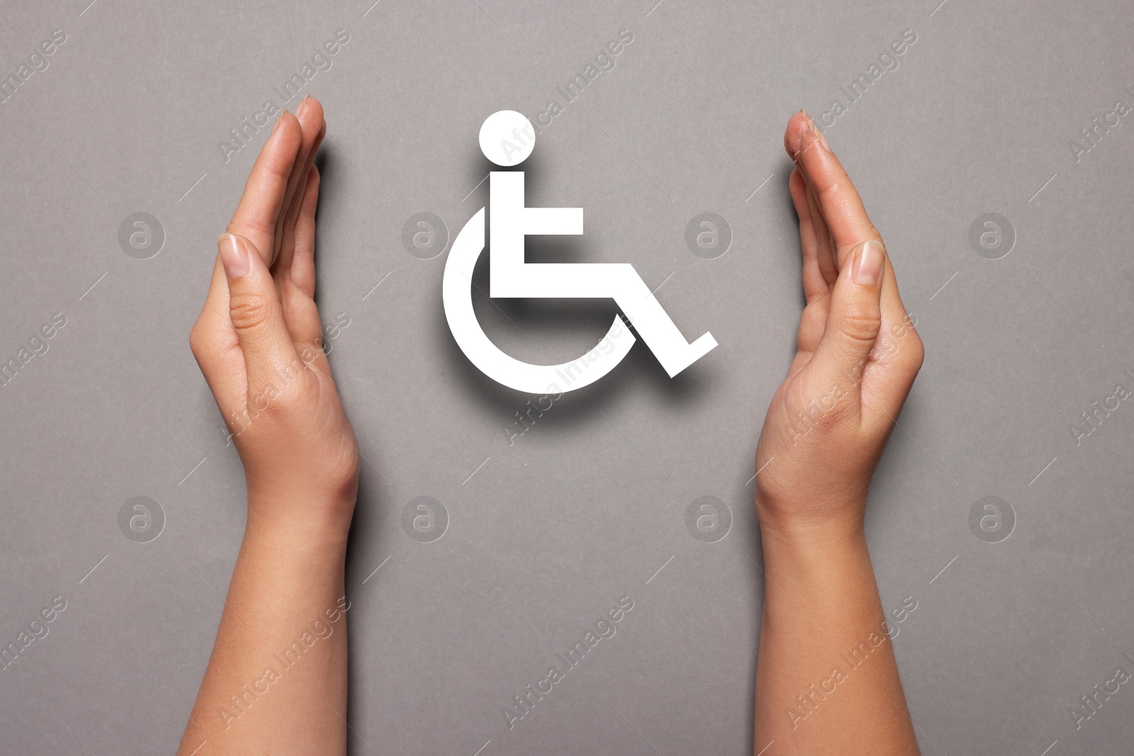 Image of Disability inclusion. Woman protecting wheelchair symbol on grey background, closeup