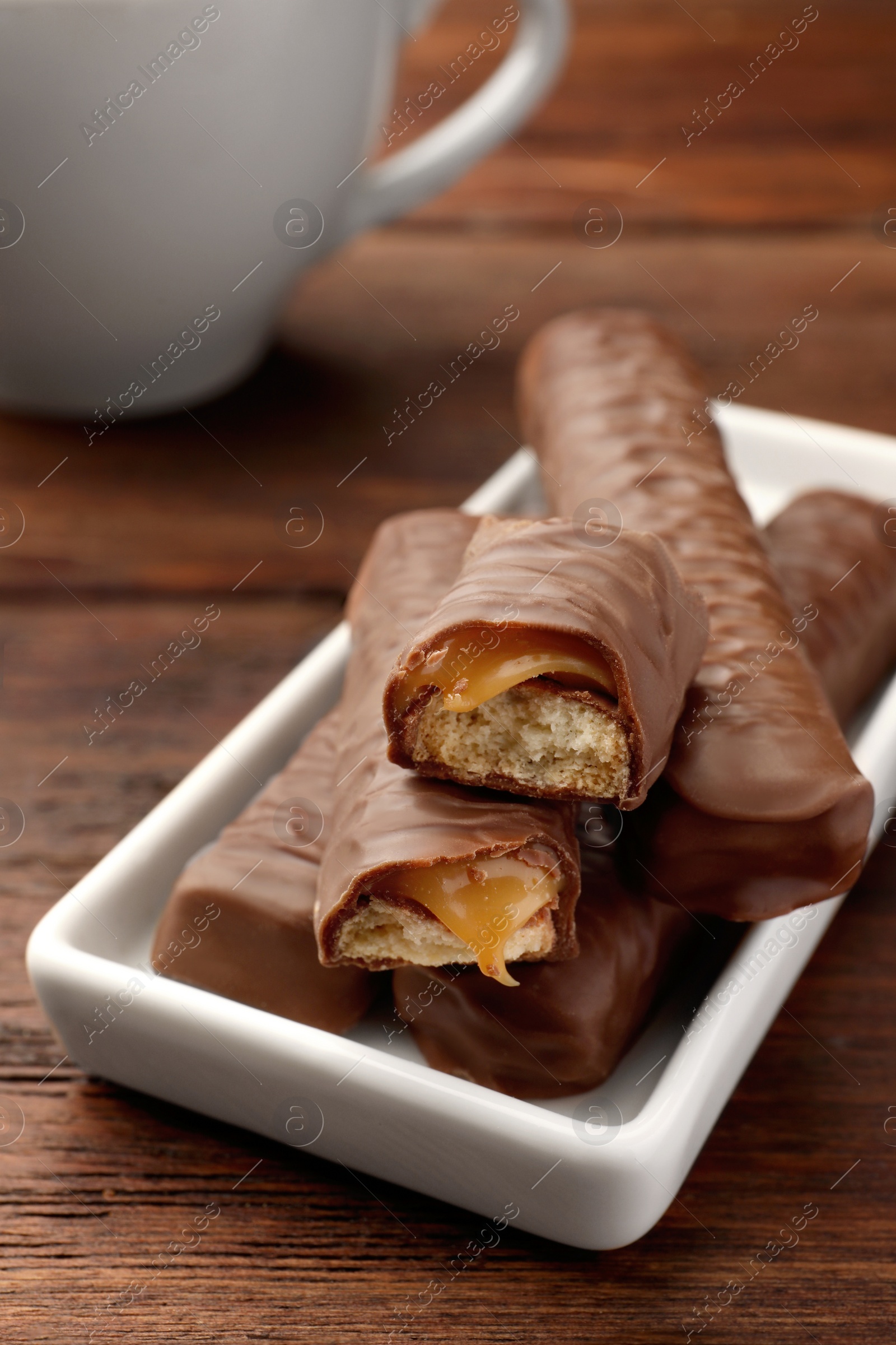 Photo of Sweet tasty chocolate bars with caramel on wooden table, closeup