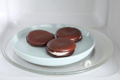Photo of Tasty sweet choco pies on plate in microwave