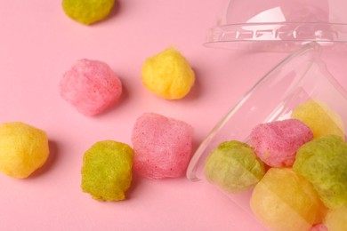 Photo of Plastic cup with color cotton balls on pink background, flat lay. Sweet candy