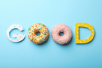 Photo of Word GOOD made with donuts and carton letters on light blue background, flat lay