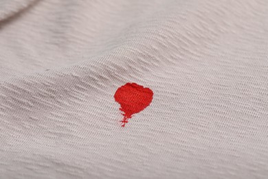 Photo of Stain of red ink on beige shirt, closeup