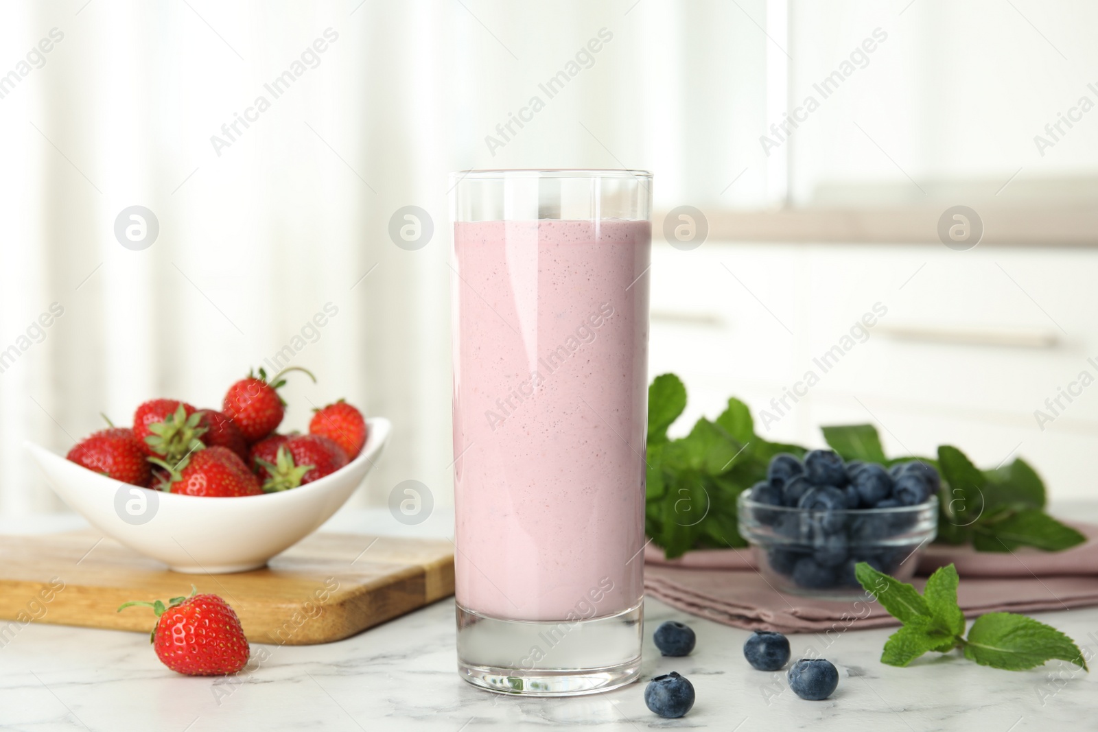 Photo of Tasty milk shake and berries on white marble table