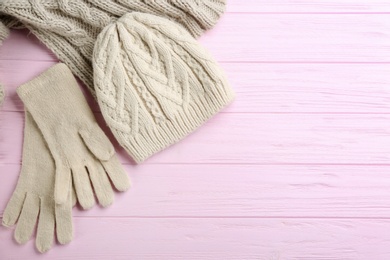 Stylish gloves, hat and scarf on pink wooden background, flat lay. Space for text
