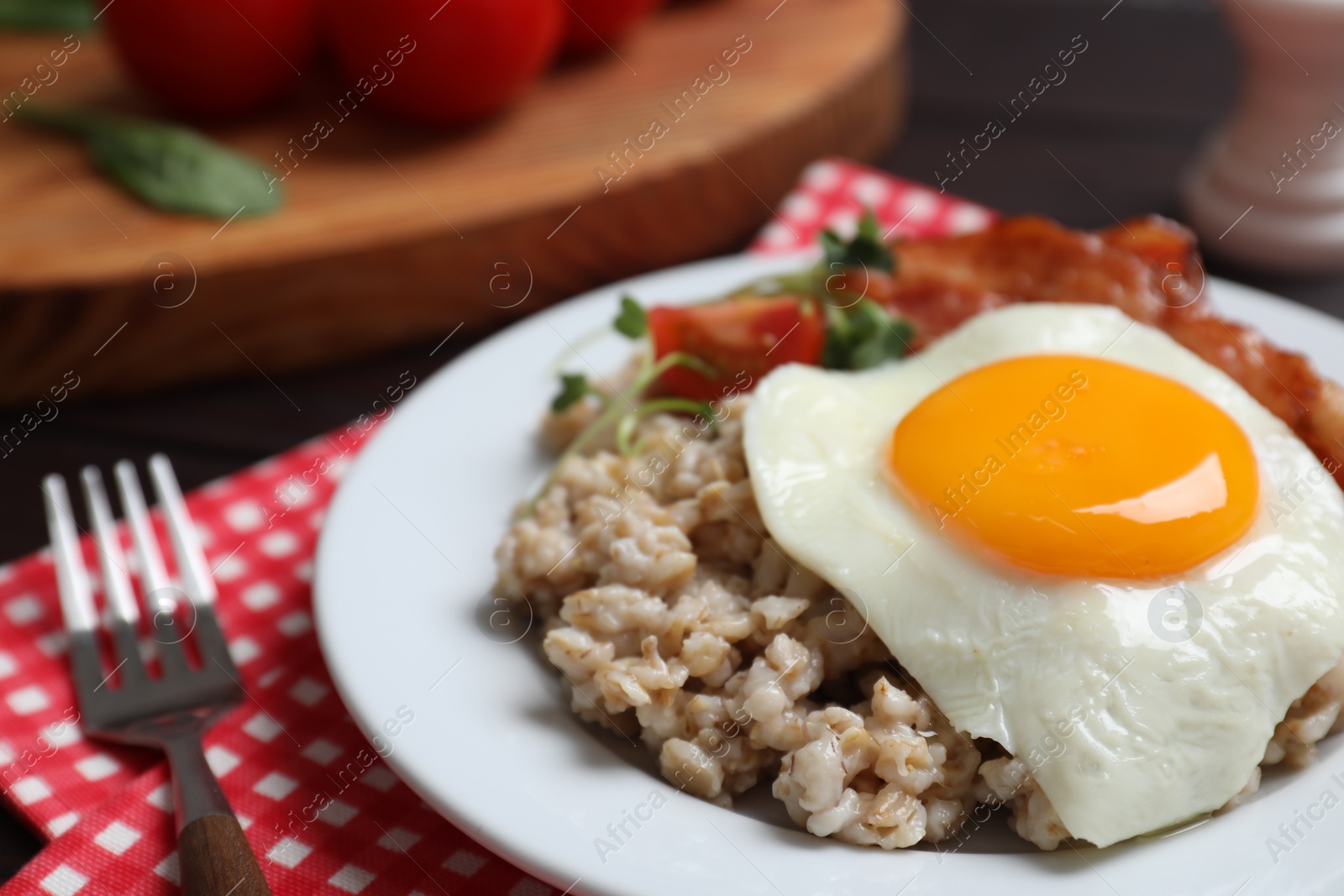 Photo of Tasty boiled oatmeal with fried egg served on table, closeup