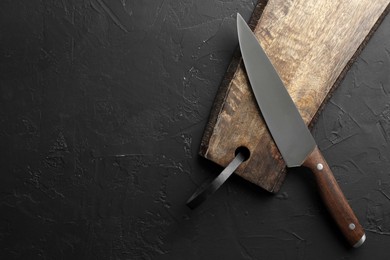 Photo of One sharp knife and board on dark textured table, top view. Space for text