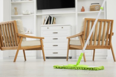 Cleaning white parquet floor with mop in room. Space for text