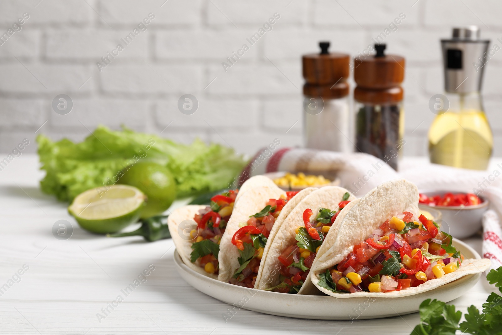 Photo of Tasty tacos with vegetables on white wooden table, space for text