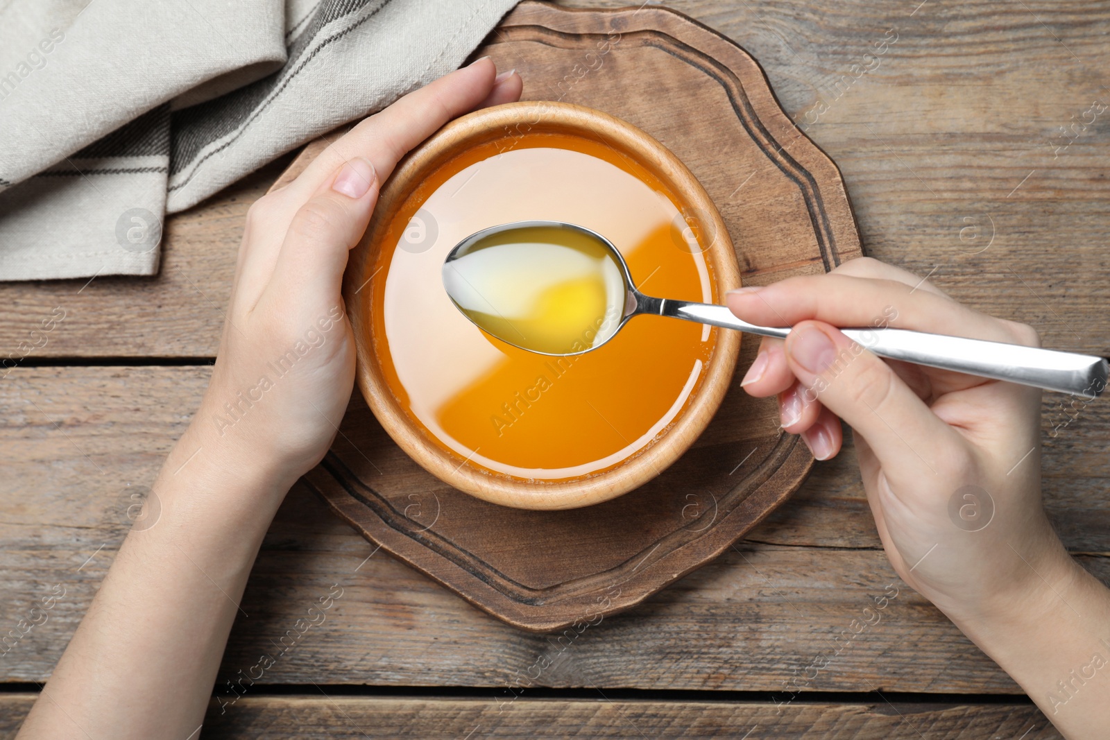 Photo of Woman with melted ghee butter at wooden table, top view