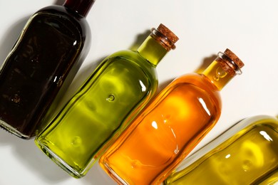 Photo of Vegetable fats. Different cooking oils in glass bottles on white background, flat lay