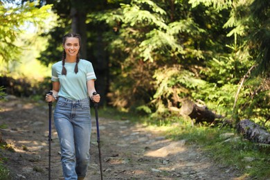 Photo of Woman with trekking poles hiking in forest
