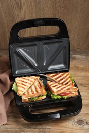 Modern grill maker with sandwiches on wooden table