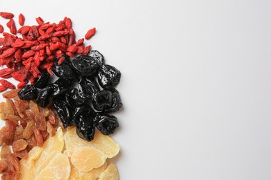 Photo of Pile of different dried fruits on white background, top view. Space for text