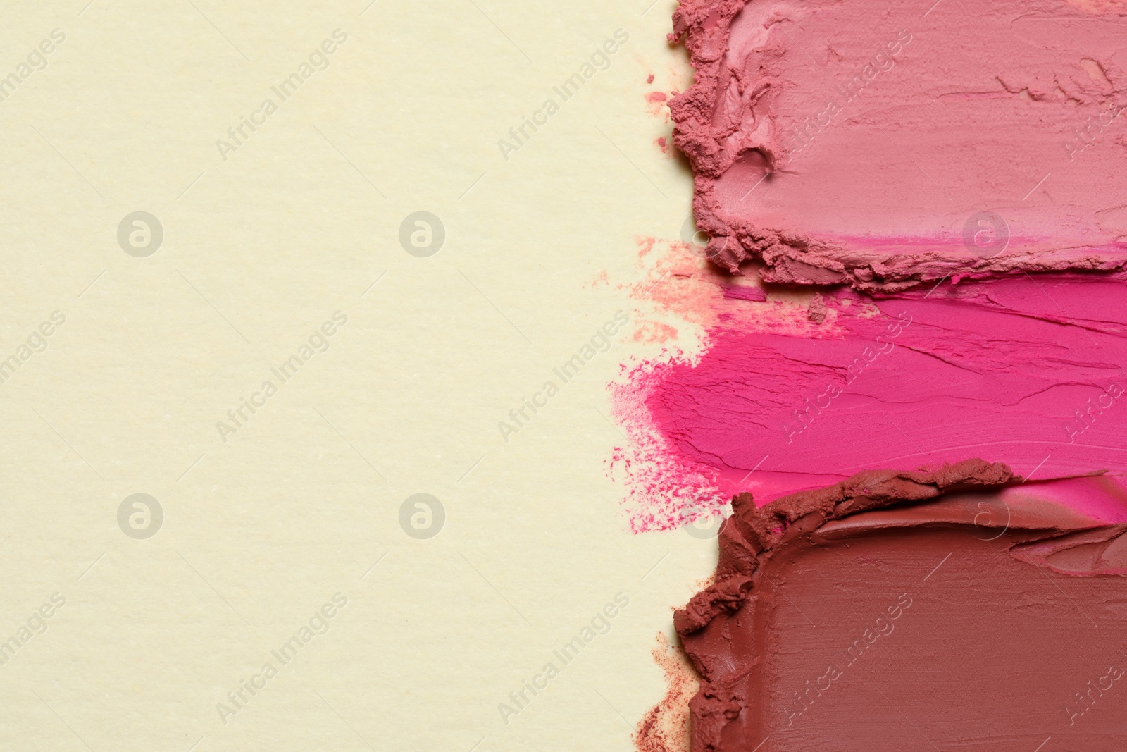 Photo of Smears of beautiful lipsticks on beige background, top view. Space for text