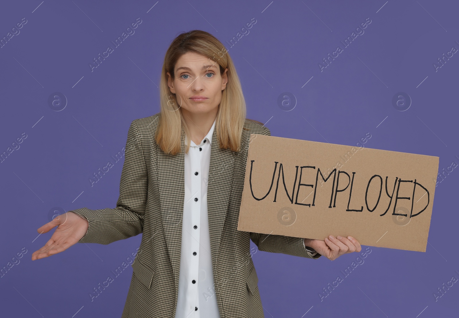 Photo of Confused woman holding sign with word Unemployed on violet background