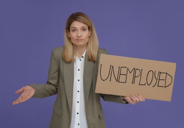 Photo of Confused woman holding sign with word Unemployed on violet background