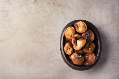 Photo of Bowl with dried figs on grey background, top view. Space for text