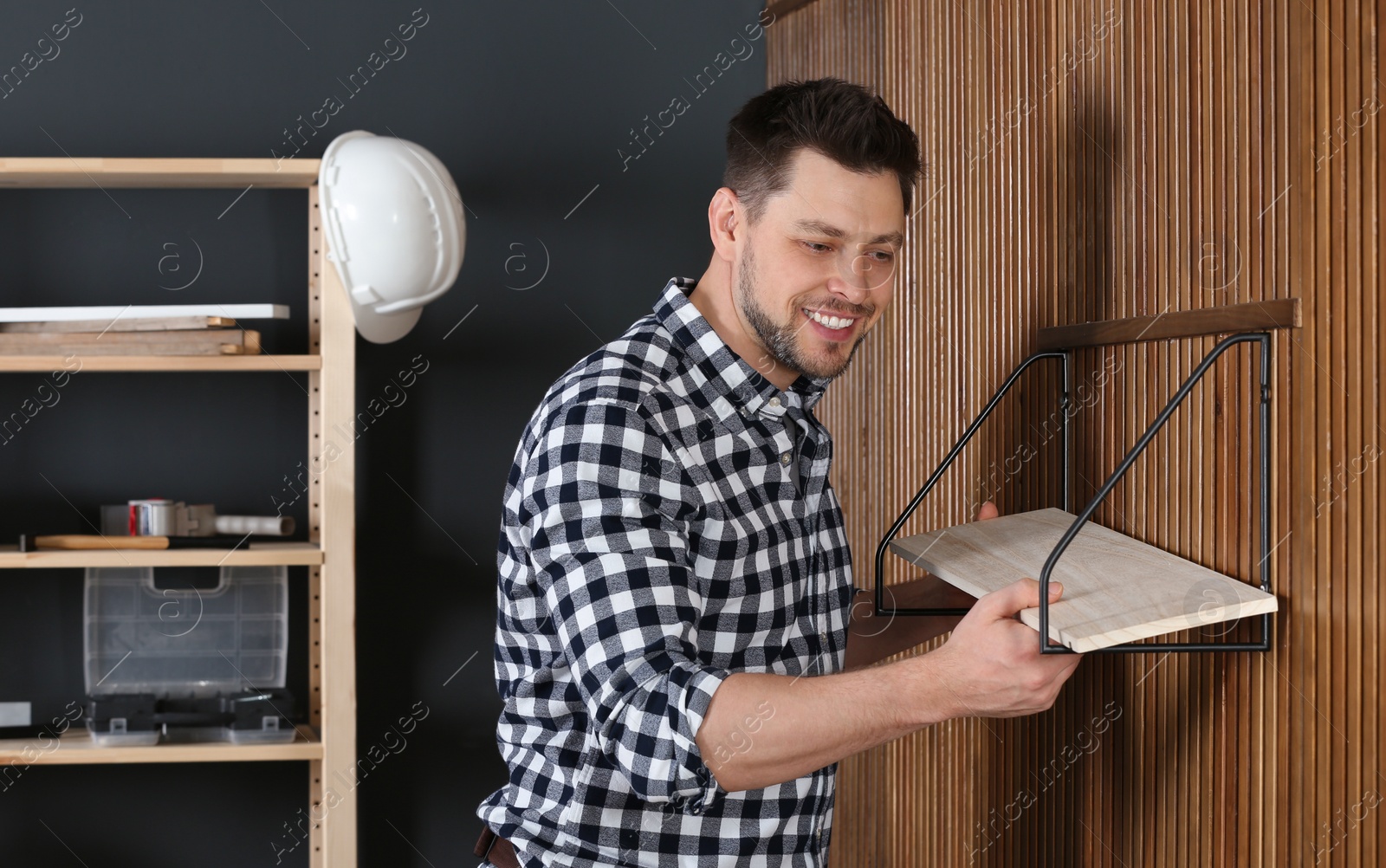 Photo of Handsome working man setting shelf indoors. Home repair